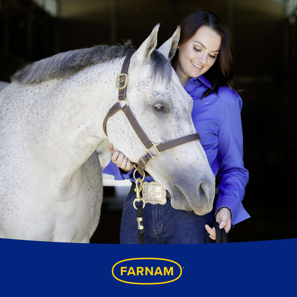 Woman smiling and petting a white horse affectionately. Farnam logo